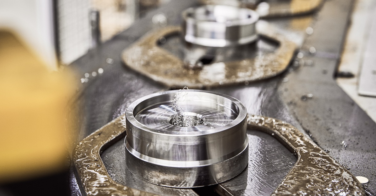 Nahaufnahme eines Metallprodukts während der Bearbeitung, umgeben von Metallspänen auf einer Werkstattfläche.