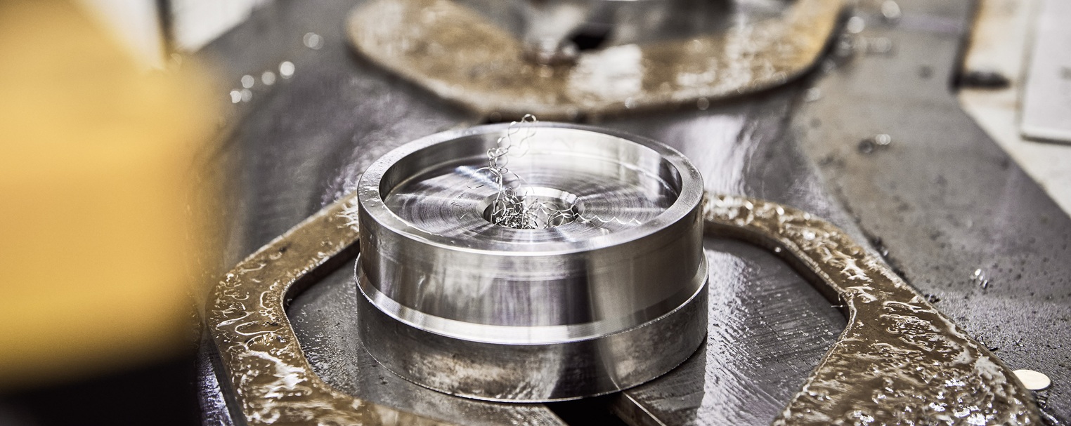 Nahaufnahme eines Metallprodukts während der Bearbeitung, umgeben von Metallspänen auf einer Werkstattfläche.