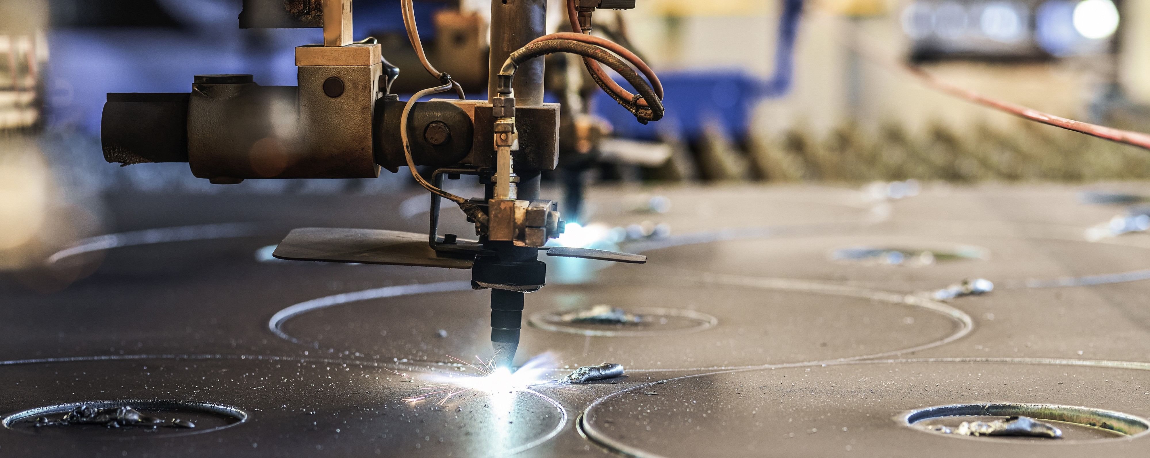 CNC-Plasmaschneidbrenner erzeugt Funken beim Schneiden kreisförmiger Muster in ein Stahlblech.