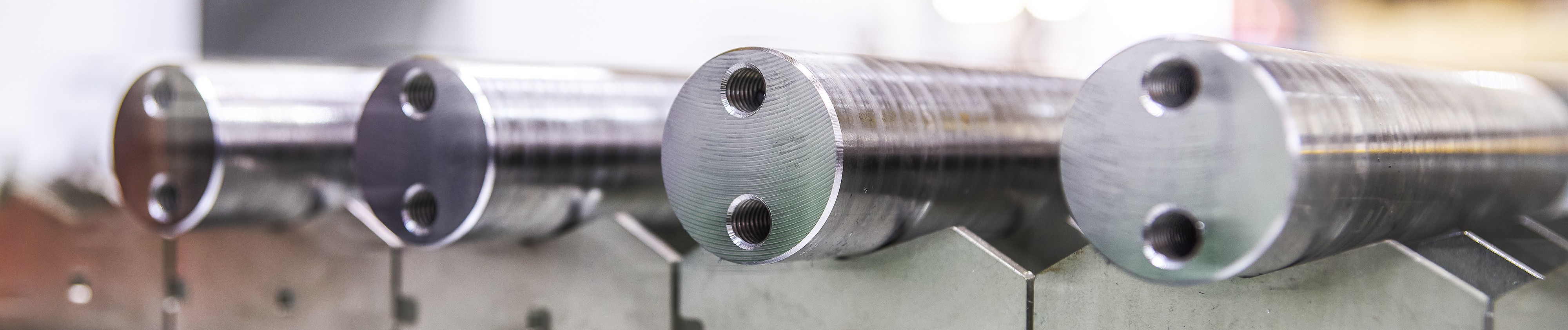 Nahaufnahme von vier zylindrischen Metallstangen, die auf V-förmigen Metallstützen ruhen.